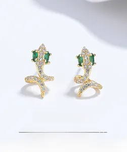 Macro shot of gold snake earrings featuring emerald eyes and white cubic zirconia crystals