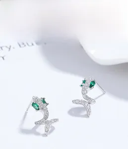 Macro shot of S925 silver dolphin earrings with white cubic zirconia and emerald eyes