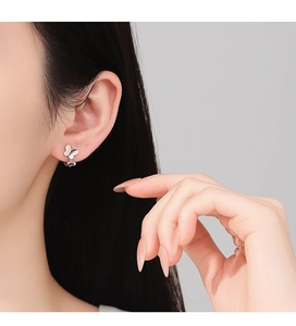 Close-up of minimalist S925 sterling silver butterfly earrings worn on the earlobe
