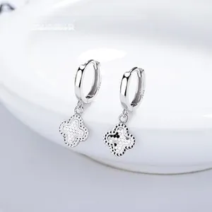 Vue macro de boucles d'oreilles créoles en argent S925 avec pendentifs trèfle dépoli