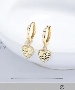 Gros plan de boucles d'oreilles cœur en argent S925 doré avec texture effet glace