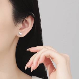 Minimalist S925 sterling silver heart stud earrings with matte brushed finish on model