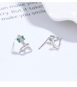 Close-up of S925 silver snake earrings with emerald eyes and pavé-set zircons on white props