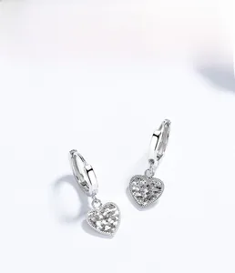 Vue macro de boucles d'oreilles cœur en argent S925 avec texture étincelante givrée