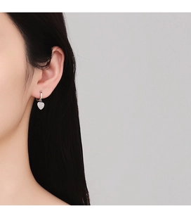 Gros plan de boucles d'oreilles cœur en argent S925 avec cristaux portées par un modèle