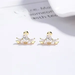 Macro detail of gold crown earrings with sparkling zircons and screw-back closure