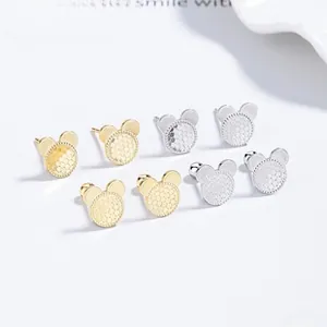 Macro detail of Mickey-shaped stud earrings in gold and silver with honeycomb texture