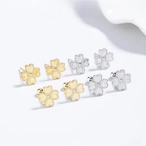 Macro detail of S925 silver clover stud earrings in matte gold and silver finishes