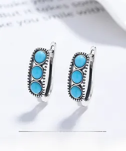 Detail of vintage S925 silver huggie earrings with three turquoise stones and beaded edge