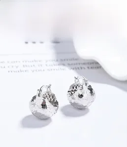 Macro detail of S925 sterling silver hollow sphere earrings with faceted laser cut texture