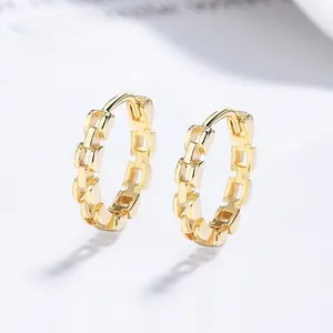 Macro detail of gold-plated chain link hoop earrings with a textured geometric pattern