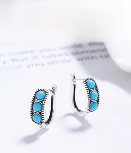Macro shot of S925 sterling silver hoop earrings with three turquoise-style round gemstones