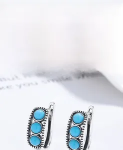 Macro detail of S925 sterling silver hoop earrings featuring three turquoise stones
