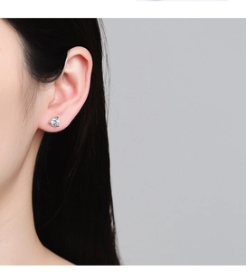 Close-up of minimalist S925 sterling silver stud earring with three-prong zircon setting