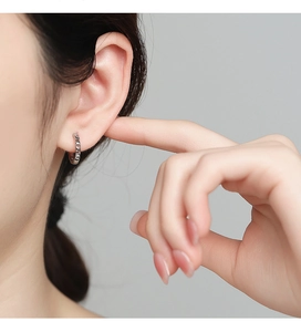 Close-up of a 925 sterling silver hoop earring with twisted braid texture worn by a model