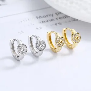 Macro view of gold and silver coin-shaped hoop earrings with micro-inlaid cubic zirconia