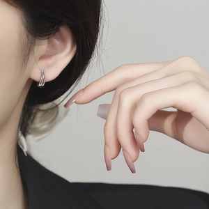 Boucles d'oreilles créoles torsadées à trois couches en argent portées par un mannequin