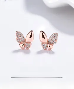 Gros plan de boucles d'oreilles papillon en or rose serties de zircons étincelants