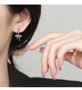 Close-up of 925 sterling silver bow earrings with sparkling pavé zircons worn on ear