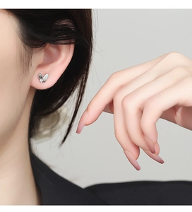 Détail d'une boucle d'oreille papillon en argent 925 avec zircons portée à l'oreille