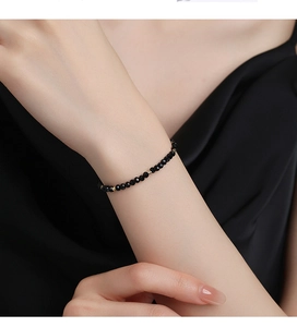 Close-up of minimalist black onyx bead bracelet with gold accents on female wrist