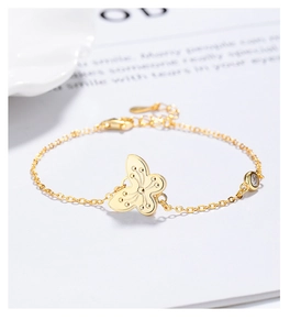 Macro detail of gold butterfly bracelet showing dot texture and white zircon stone