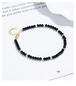Detail of faceted black onyx beads and golden cylinder spacers with adjustable chain