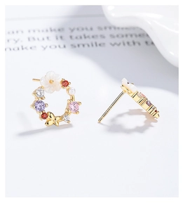 Close-up of gold butterfly flower hoop earrings with colorful cubic zirconia and pearls