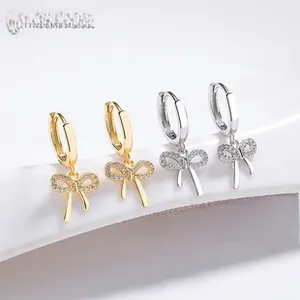 Détail de boucles d'oreilles nœud papillon serties de zircons en or et argent poli