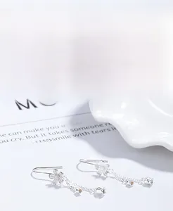 Detailed macro view of S925 silver camellia flower earrings with fine tassel chains