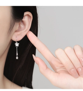 Detailed close-up of a silver camellia tassel earring worn elegantly on a model