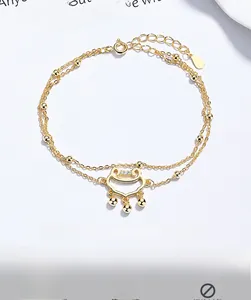 Detail of a double-layered gold bead bracelet with a hollowed-out lock charm on white surface
