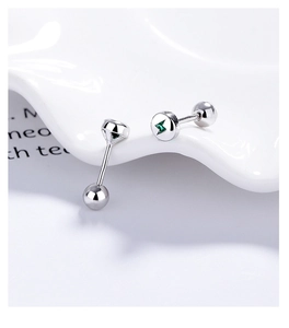 Macro shot of silver screw-back earrings with green lightning bolt in polished round discs