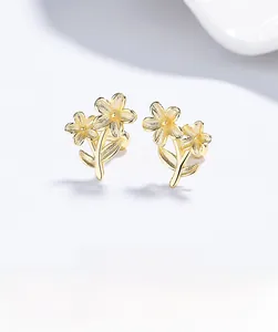 Macro detail of 18K gold flower earrings with brushed texture and screw back design