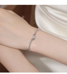 Makroaufnahme eines 925er Silber-Armbands mit Zirkonia-Schleife am Handgelenk der Frau