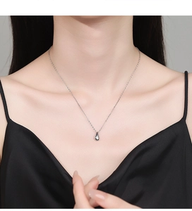Elegant 925 silver teardrop pendant necklace worn on neck with a black silk dress
