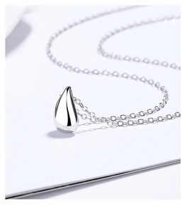 Macro shot of a polished silver teardrop pendant with minimalist sterling chain detail