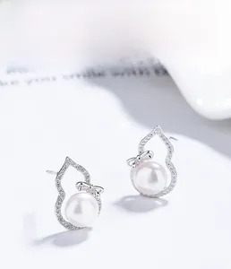 Macro shot of S925 silver pearl stud earrings with zircon bow and hollow gourd design