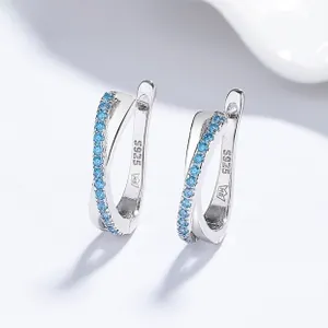 Macro detail of S925 silver crossover earrings with sparkling blue zircon inlay