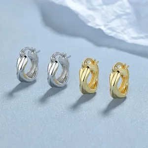 Detail view of intertwined twisted rope hoop earrings in polished silver and gold finishes
