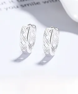 Macro view of silver hollow mesh cross hoop earrings with elegant polished finish