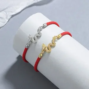 Detail of red braided dragon bracelets with gold and silver crystal zodiac pendants