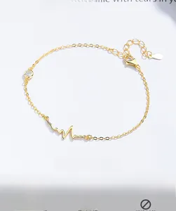 Detail of gold heartbeat bracelet featuring a white zircon stone and adjustable lobster clasp
