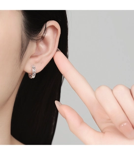 Close-up of hollow geometric silver hoop earring worn on model for minimalist style