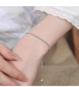 Detail view of adjustable silver beaded bracelet on wrist with elegant lace clothing
