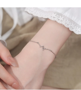Detailed view of silver heartbeat zircon bracelet on wrist against soft lace fabric