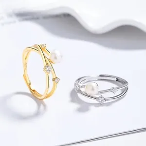 Detailed view of adjustable silver and gold rings with pearls and sparkling zircons