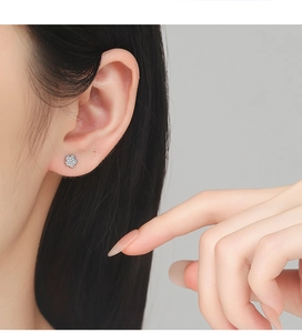 Close-up of 925 silver flower stud earring with sparkling zircons on model ear