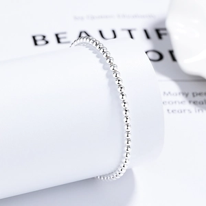 Minimalist 925 sterling silver beaded bracelet on a white cylinder stand with a high-end feel