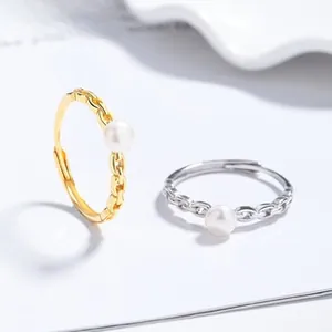 Close-up of gold and silver chain rings with white pearls on a minimalist background
